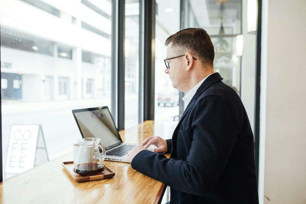 A businessperson works on their laptop at a coffeeshop.