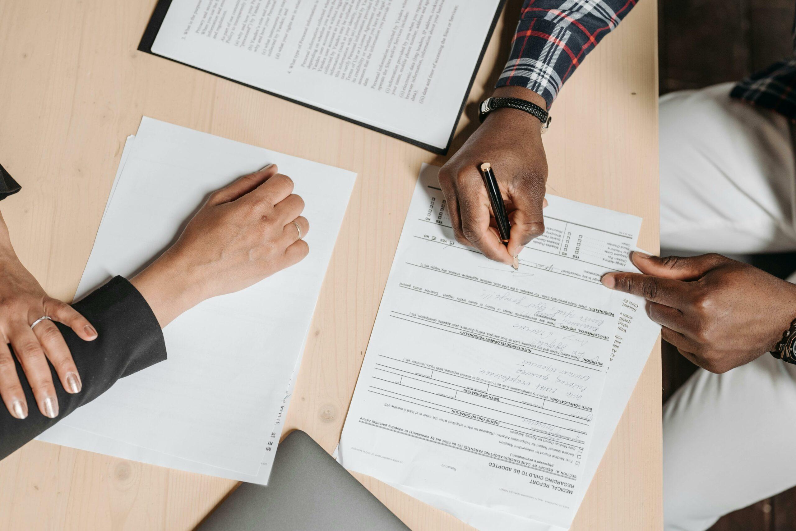 lender-borrower-filling-out-form-together A businessperson helps someone fill out a form.