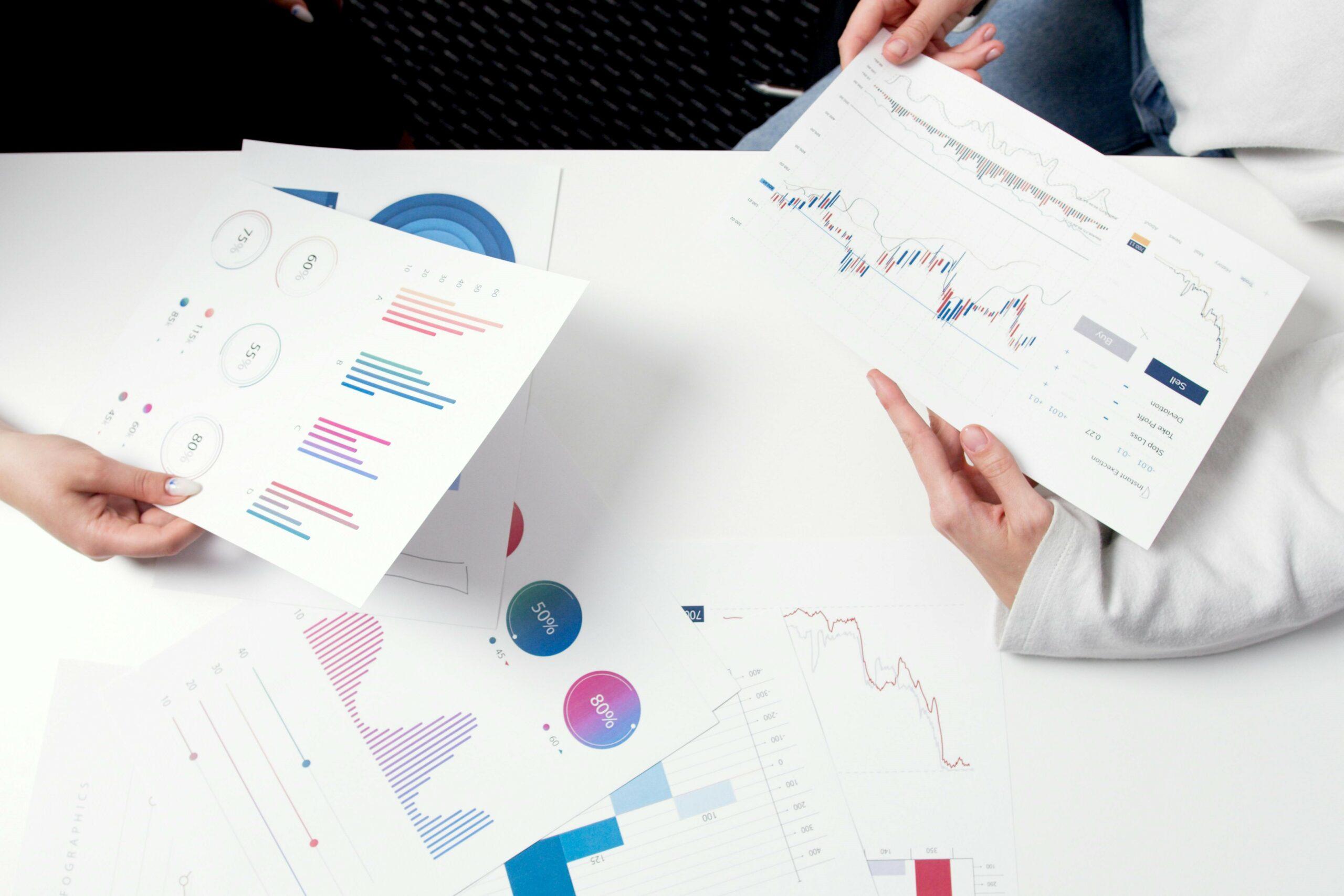 lender-employees-analyzing-business-financials Two lender employees study a business's colorful, graph-filled financial documents.